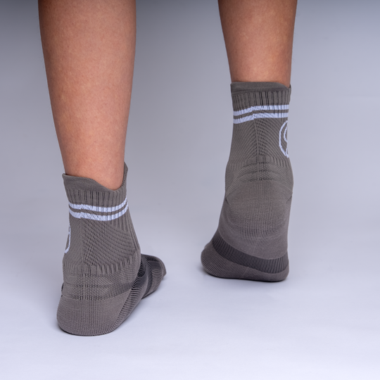 Gray socks with white stripes worn by a person on a plain background