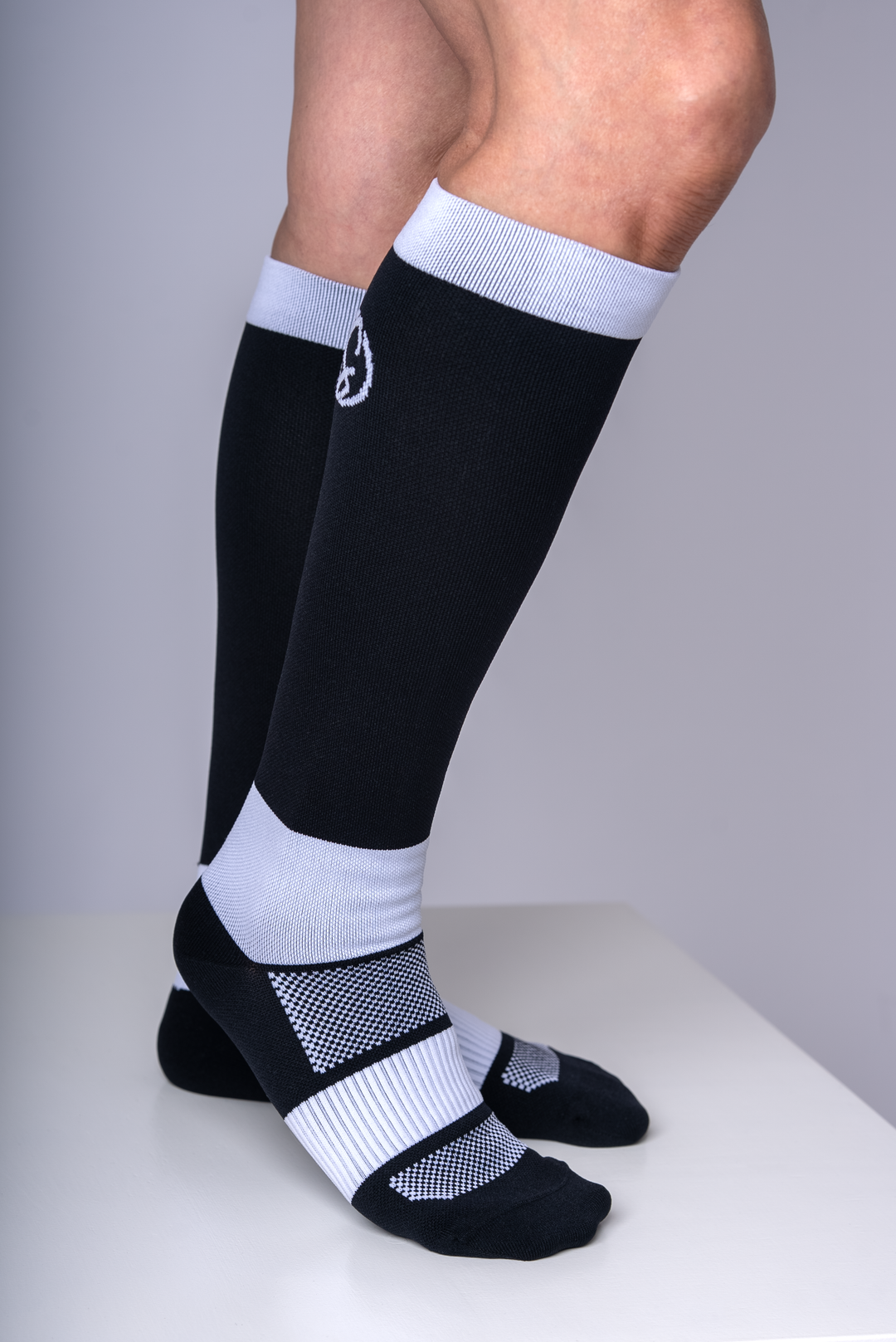 Black and white knee-high socks worn by a person on a gray background