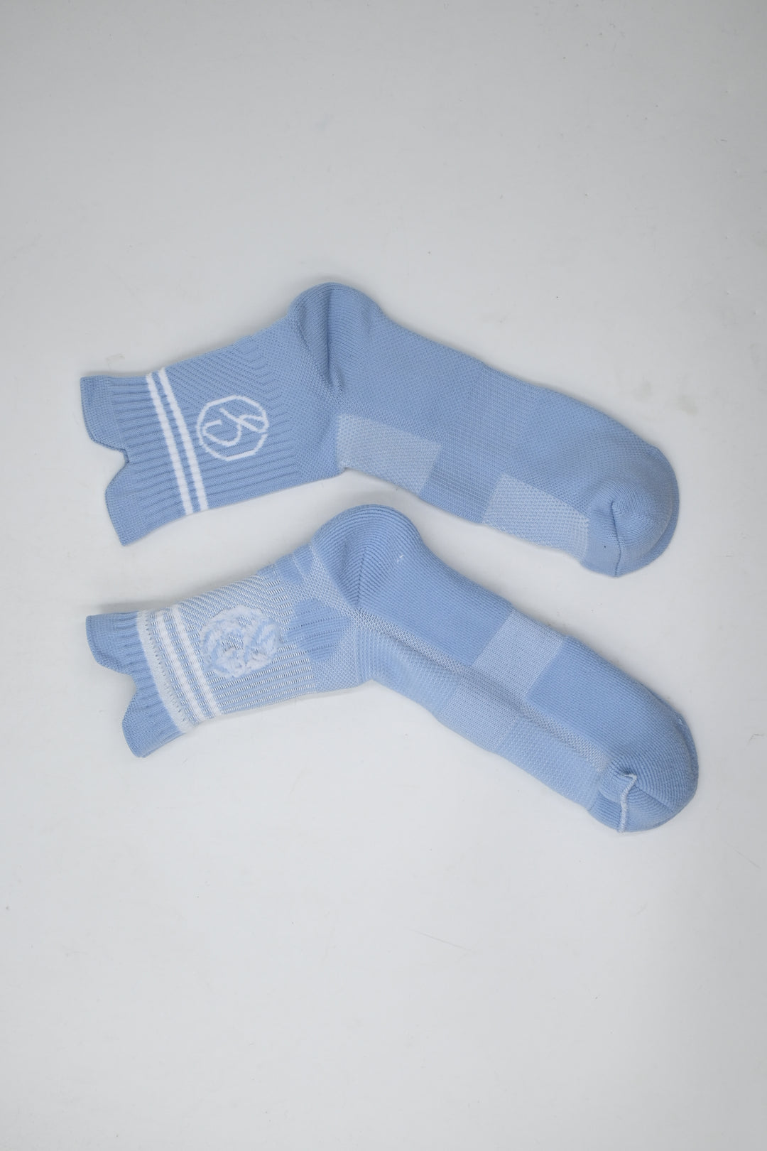 Pair of light blue socks with white stripes on a gray background