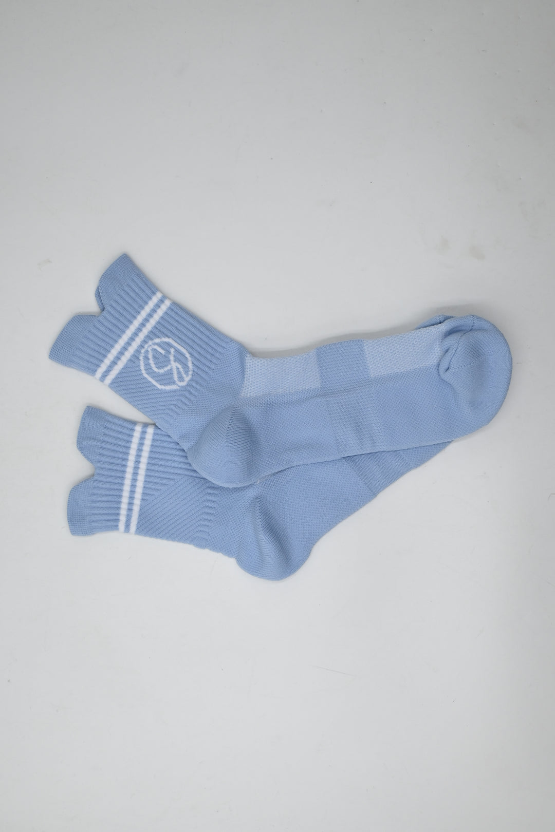 Pair of light blue socks with white stripes on a gray background